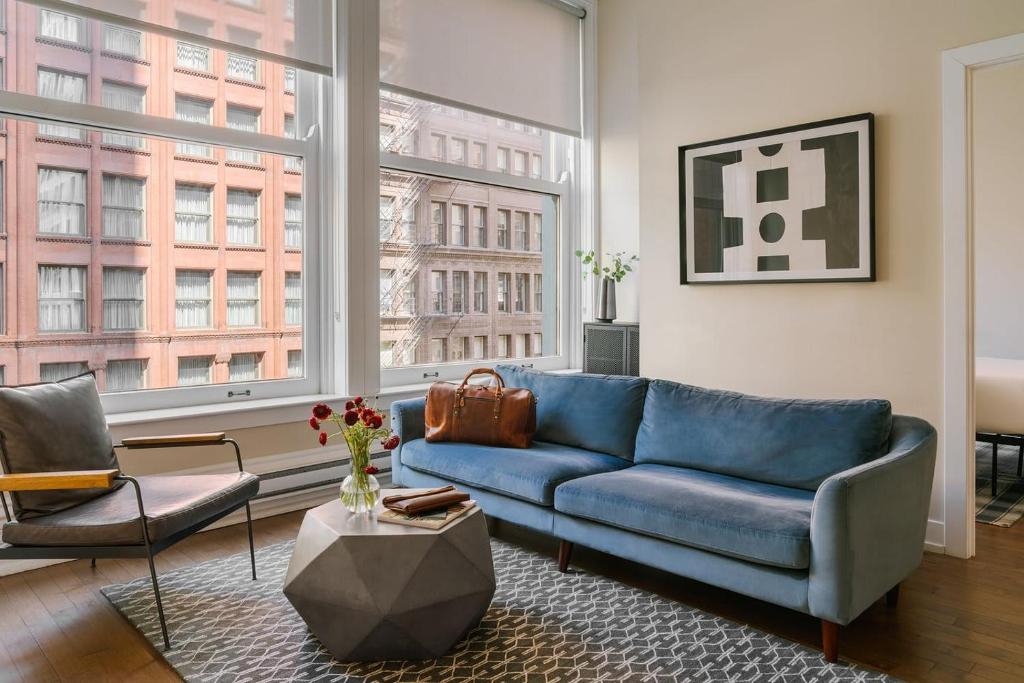 a living room with a blue couch and a large window at LIVN Millennium Park Downtown Chicago Superior 2 BR in Chicago