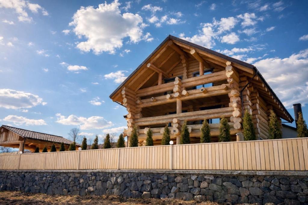 a log cabin with a fence and a blue sky at Derevo House in Yasinya