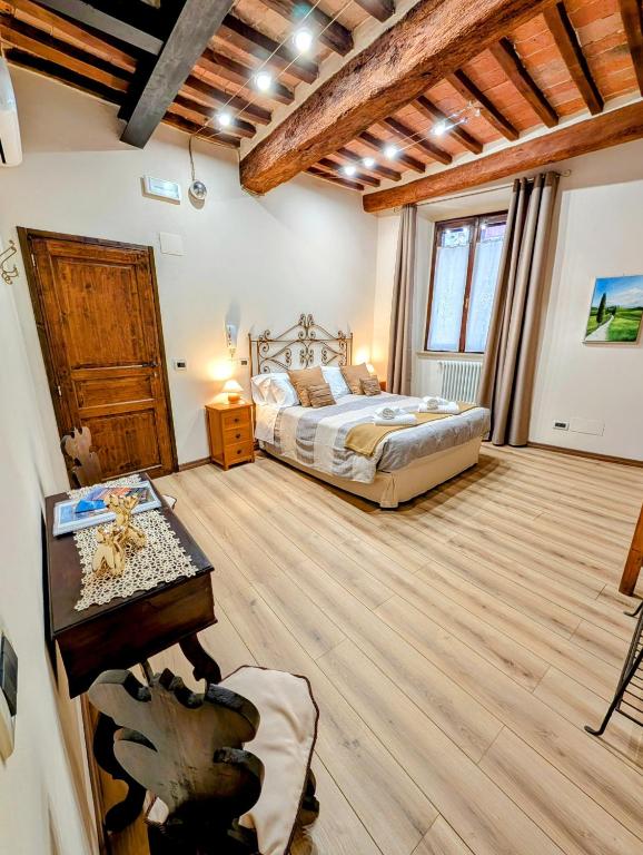 a bedroom with a bed and a wooden floor at PienzaLettings Studio & Room in Pienza