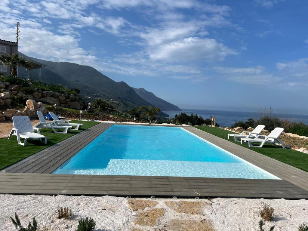 a swimming pool with two lounge chairs next to a house at La Finestra sul Mare dello Zingaro in Scopello