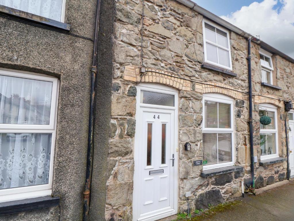 a stone building with a white door and windows at Hill View in Bala