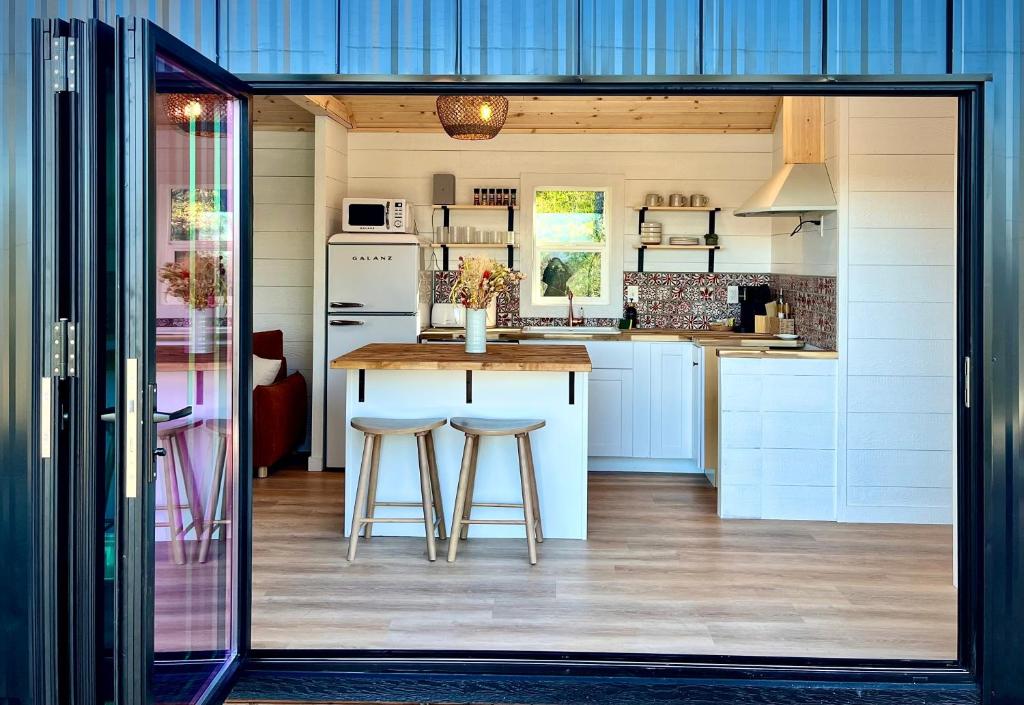 a kitchen with a counter and stools in it at Yosemite Chalet, Spacious Tiny Home with Mountain Views! in Coarsegold