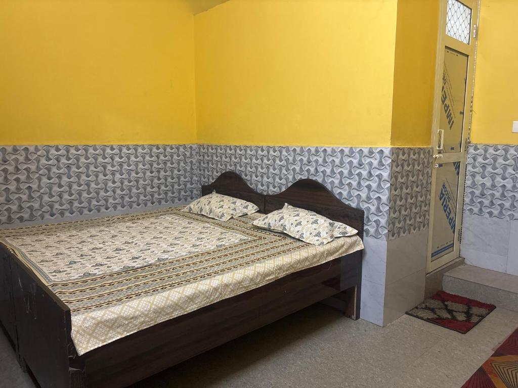 a small bed in a room with a yellow wall at Ambe hotel purnagiri in Tanakpur