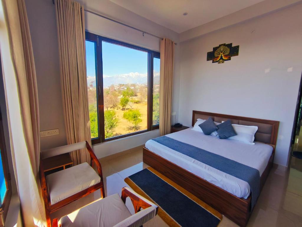 a bedroom with a bed and a large window at AeroVale Lodge I Mountain View Stay Near Landing Site Bir Billing in Bīr