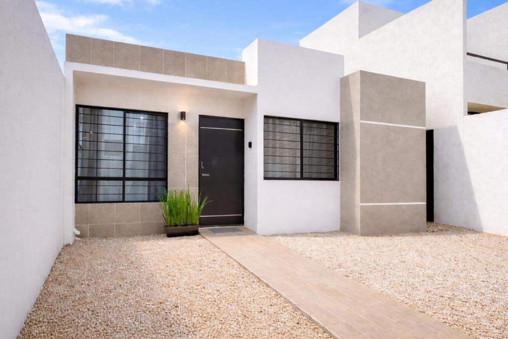 a white house with a black door at Casa Izamal Mérida in Mérida