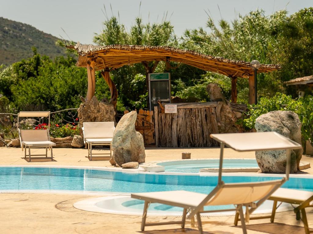 a swimming pool with chairs and a pergola at Hotiday Rooms Porto Rotondo in Porto Rotondo