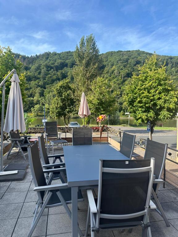 a table with chairs and umbrellas on a patio at UferZeit - Dein Ankerplatz an der Mosel in Ediger-Eller