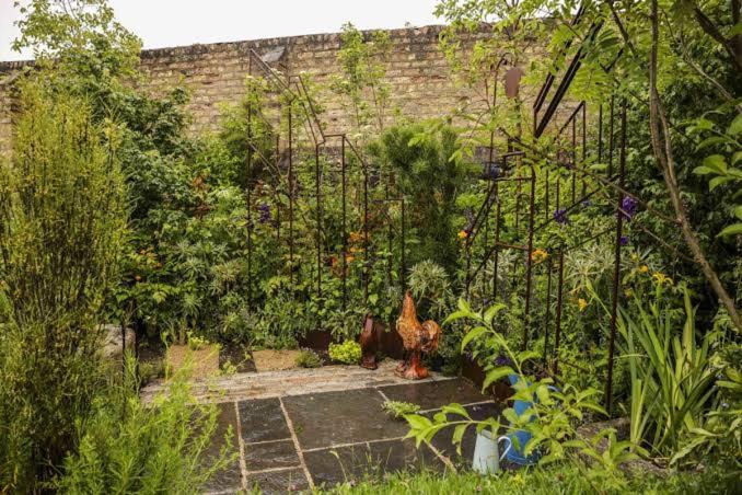 a garden with two chickens standing in front of a brick wall at Bloom Manor in Skegby