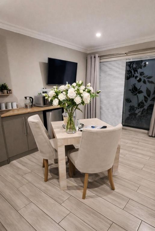 a dining room with a table with a vase of flowers at Bella Rosa in Potchefstroom