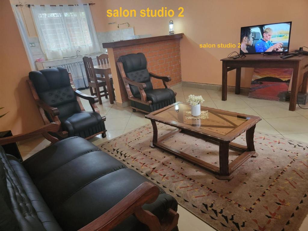 a living room with a table and chairs and a television at IVATO Airport STUDIOS CHAMBRES in Ivato