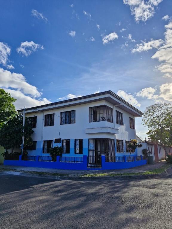 a white building with a blue fence next to a street at Hostel Casa Mar in Liberia