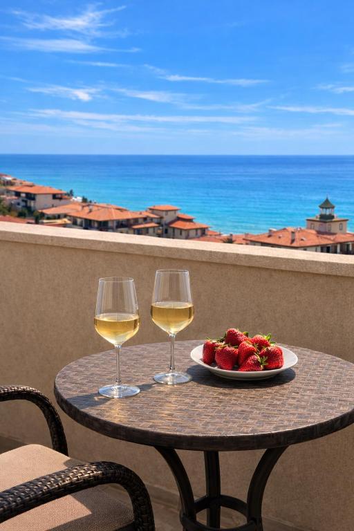 a table with a plate of strawberries and two glasses of wine at Sea Vista Hotel in Sveti Vlas