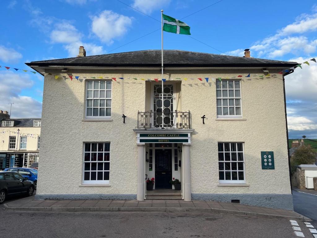 a white building with a flag on top of it at Colcombe Castle Hotel in Colyton