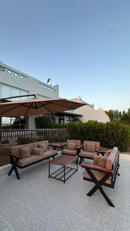 a patio with couches and tables and an umbrella at درة العروس البرادايس دور علوي عوائل فقط in Durat Alarous