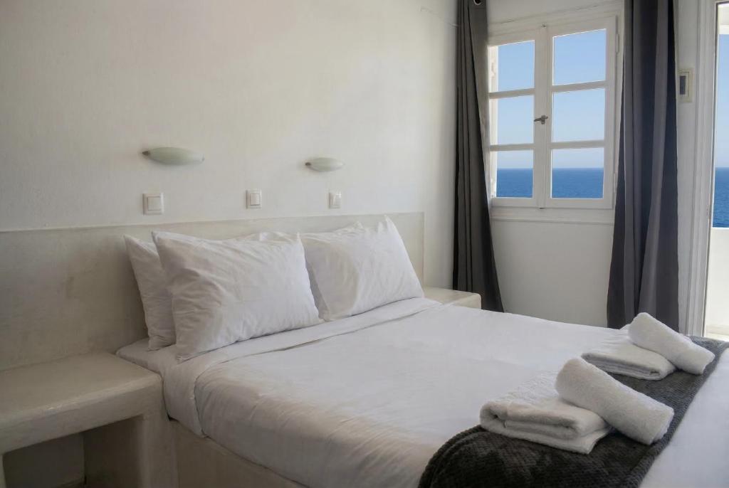 a bedroom with a white bed with towels on it at Aegean Nest Beach Studios - Adults only in Monolithos
