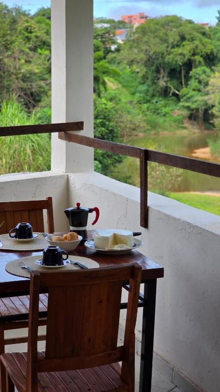 a wooden table with plates of food on a balcony at Beira Rio Casa Canastra in Vargem Bonita