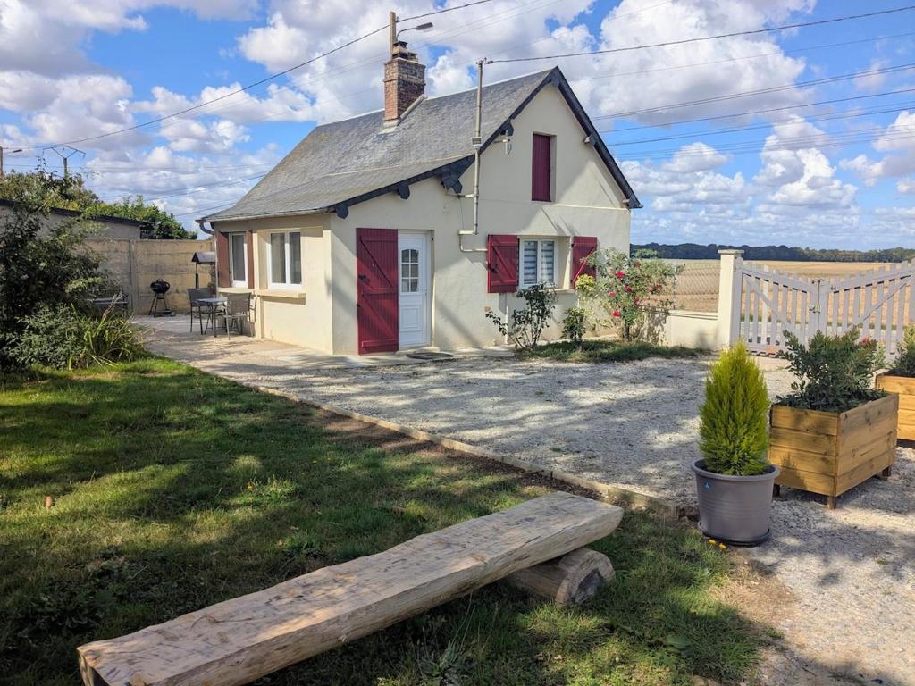 a small white house with a bench in the yard at La petite maison de Sandra in Le Plessis-Grohan