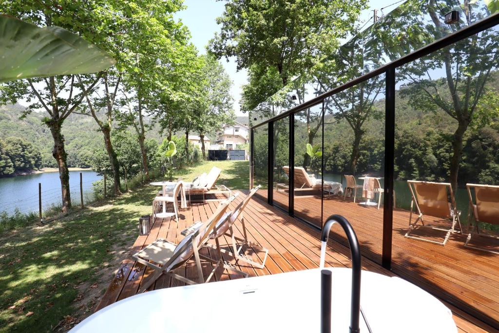 a deck with chairs and a table with a view of a river at VILLA La Finca - Privada in Vieira do Minho