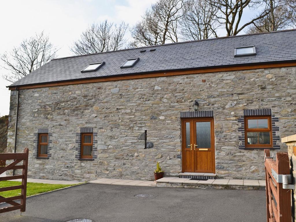 a stone building with a wooden door and windows at Helygen in Talybont