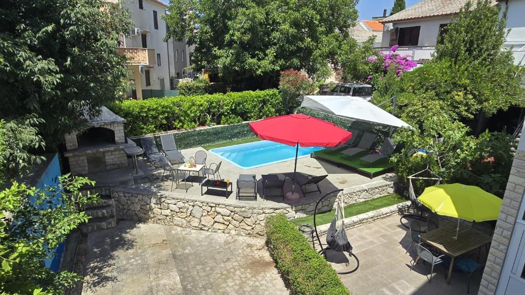 an overhead view of a swimming pool with a red umbrella and chairs at CENTRO POOL House in Novalja