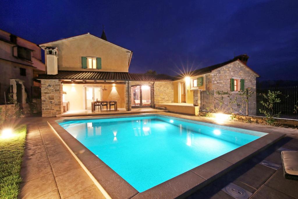 a swimming pool in front of a house at night at Villa Benvenuti in Motovun
