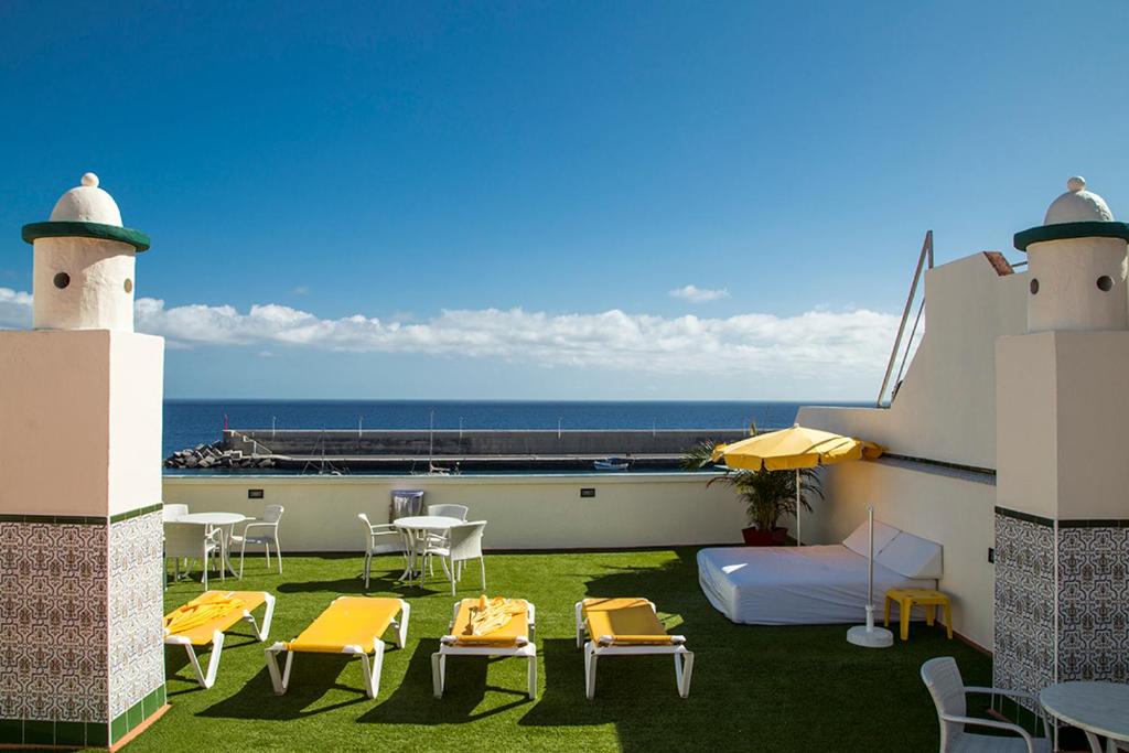 a balcony with chairs and a bed and a table at Apartamentos Tapahuga in Playa de Santiago