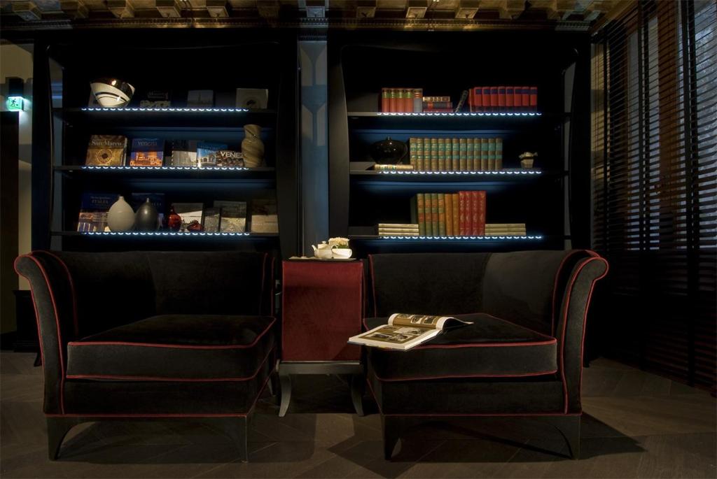 two chairs and a table in front of a book shelf at Hotel Palazzo Barbarigo Sul Canal Grande in Venice