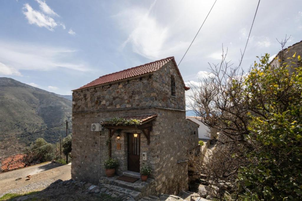 an old stone house on the side of a mountain at Manoli's Light Stone House in Vathi