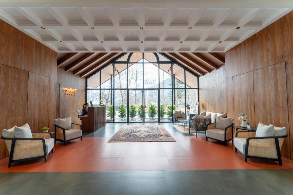 a lobby with chairs and a large window at Nivasana Manali - A Luxury Boutique Hotel in Manāli