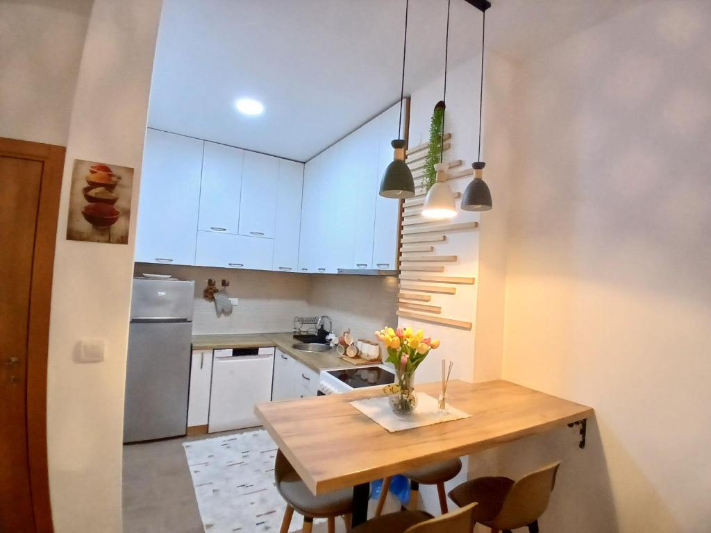 a kitchen with white cabinets and a wooden table at Jednosoban stan Tivat in Tivat