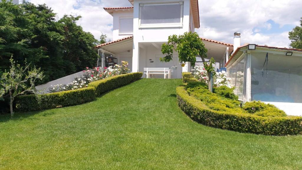 a house with a yard with green grass and flowers at White and Blue in Mesimvría