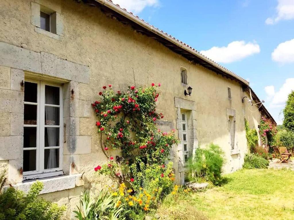 a building with flowers on the side of it at Longère de charme en pleine nature in Chillac