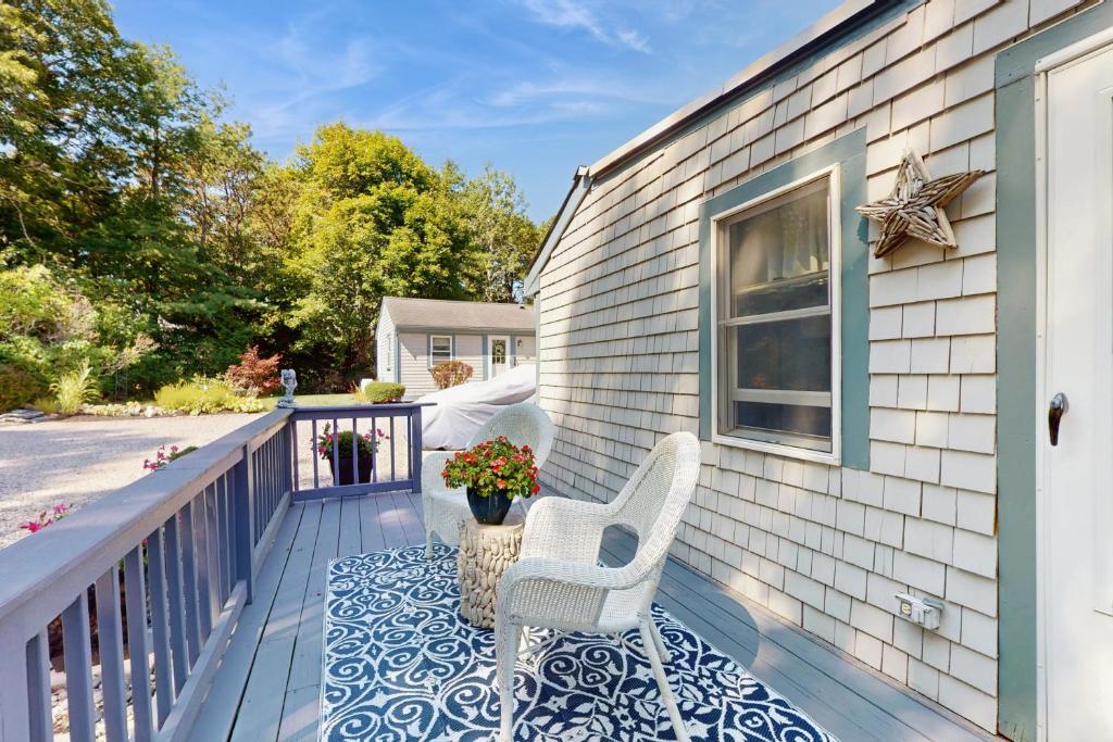 a blue and white porch with two chairs and a window at 2 Mi to Dowses Beach! Couples Haven in Osterville in Osterville