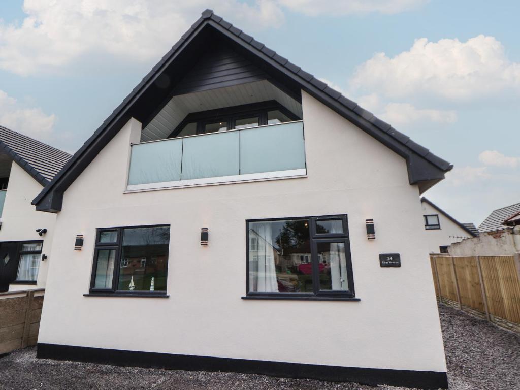 a white house with black windows at Mikes Place On The Cove in Rhyl