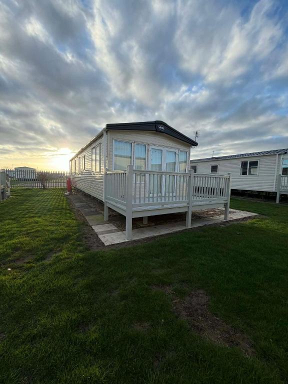 a white house with a bench in a yard at 6 berth caravan in Ingoldmells opposite beach in Ingoldmells
