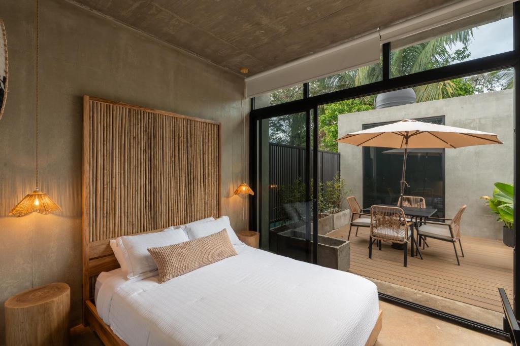 a bedroom with a bed and a patio with a table at The Digital Nomad Den in Jacó