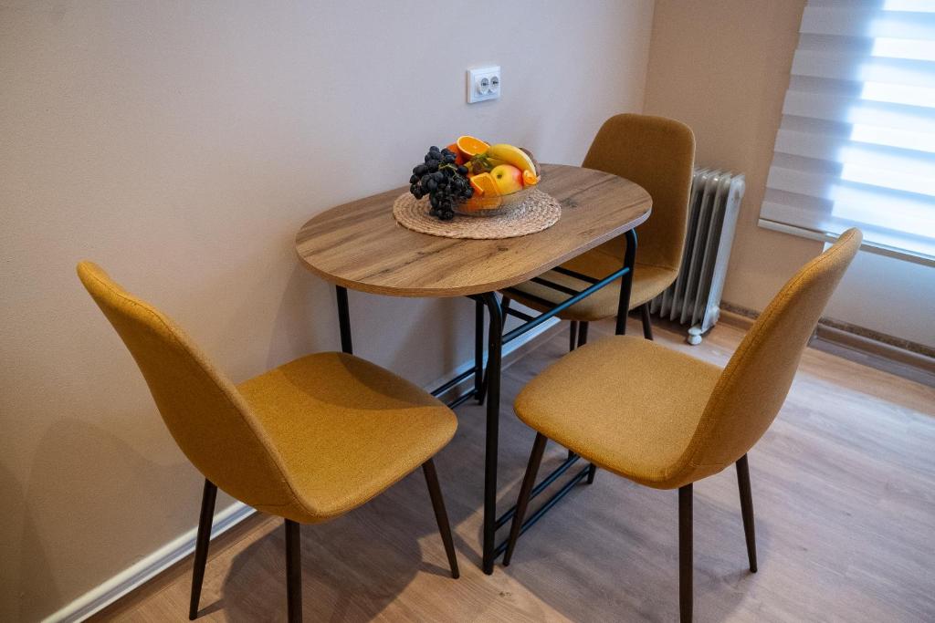 a table with chairs and a bowl of fruit on it at Apartmani Prestige in Gornji Vakuf