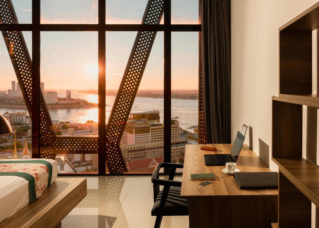 a hotel room with a desk and a large window at The Snowbell Hotel & Spa at The Bridge in Phnom Penh
