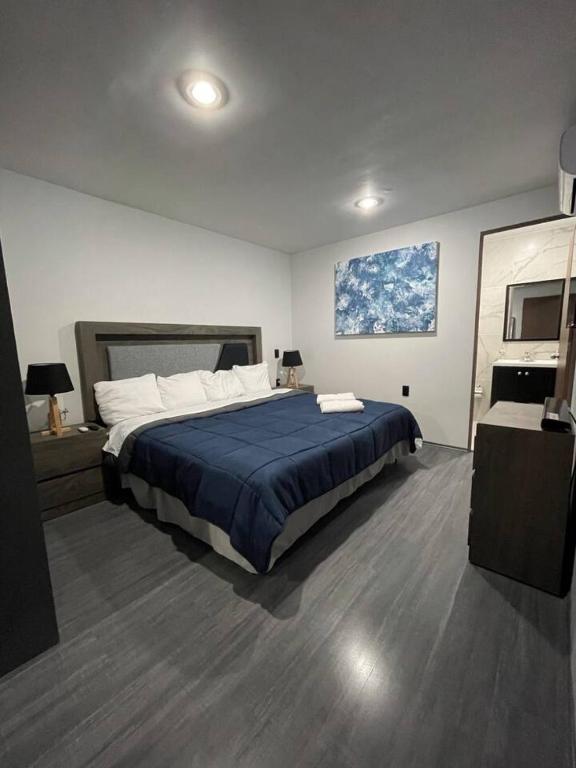 a bedroom with a large bed with a blue blanket at AR SUITES DEPARTAMENTO CENTRO 3 in Zamora de Hidalgo