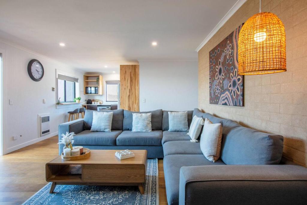 a living room with a blue couch and a table at Stunning Water Views 3 in Jindabyne
