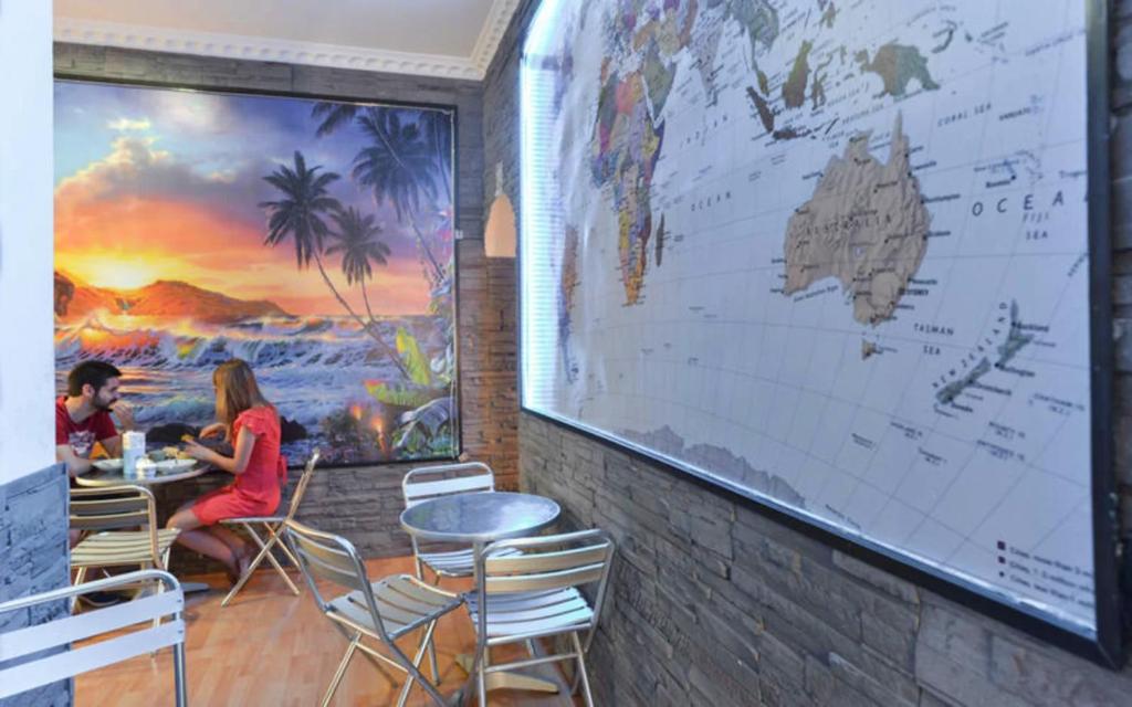 Ein Paar sitzt in einem Restaurant an einem Tisch, an der Wand hängt eine Landkarte. in der Unterkunft Ogbay Backpackers Haven in Rom