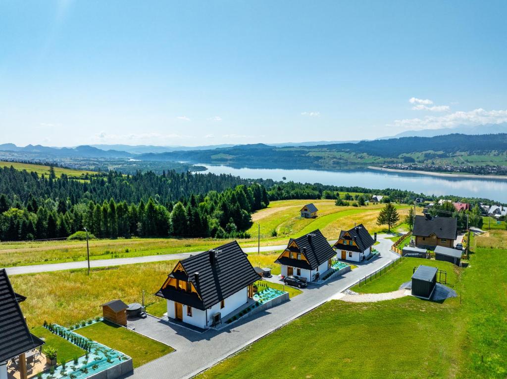 a row of cottages with a lake in the background at Osada Widokówka- Przystanek Podhale in Czorsztyn
