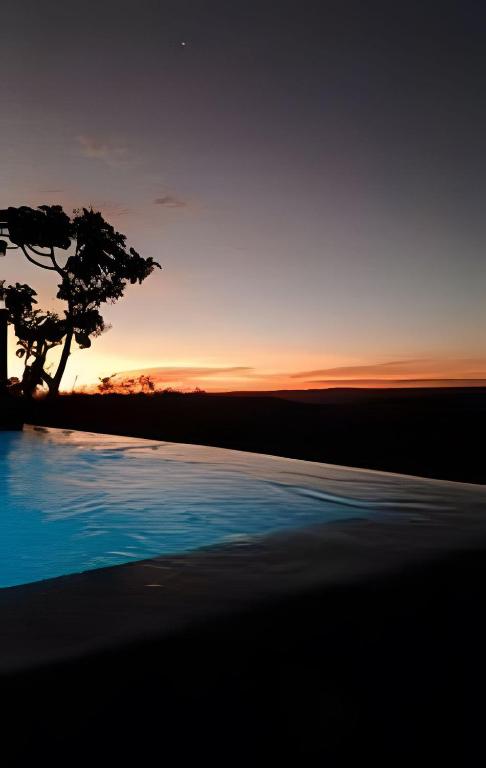 a tree sitting next to a pool at sunset at Santo Cipó - Cabanas Românticas pertinho de BH - Privacidade total e vista deslumbrante in Jaboticatubas