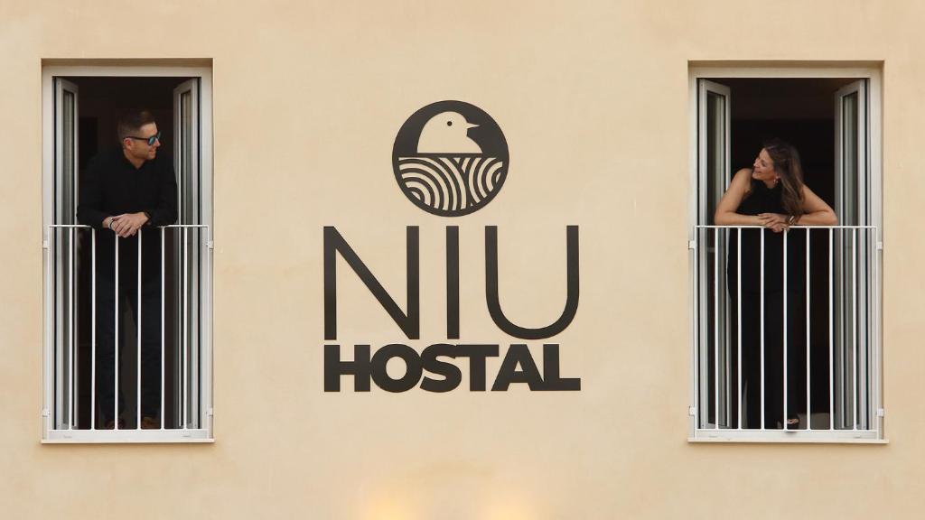 a group of people looking out the windows of a building at Niu Hostal in Casinos