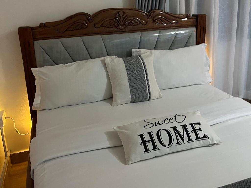 a white bed with a pillow with a sweet home sign on it at Haven Studio in Ongata Rongai 