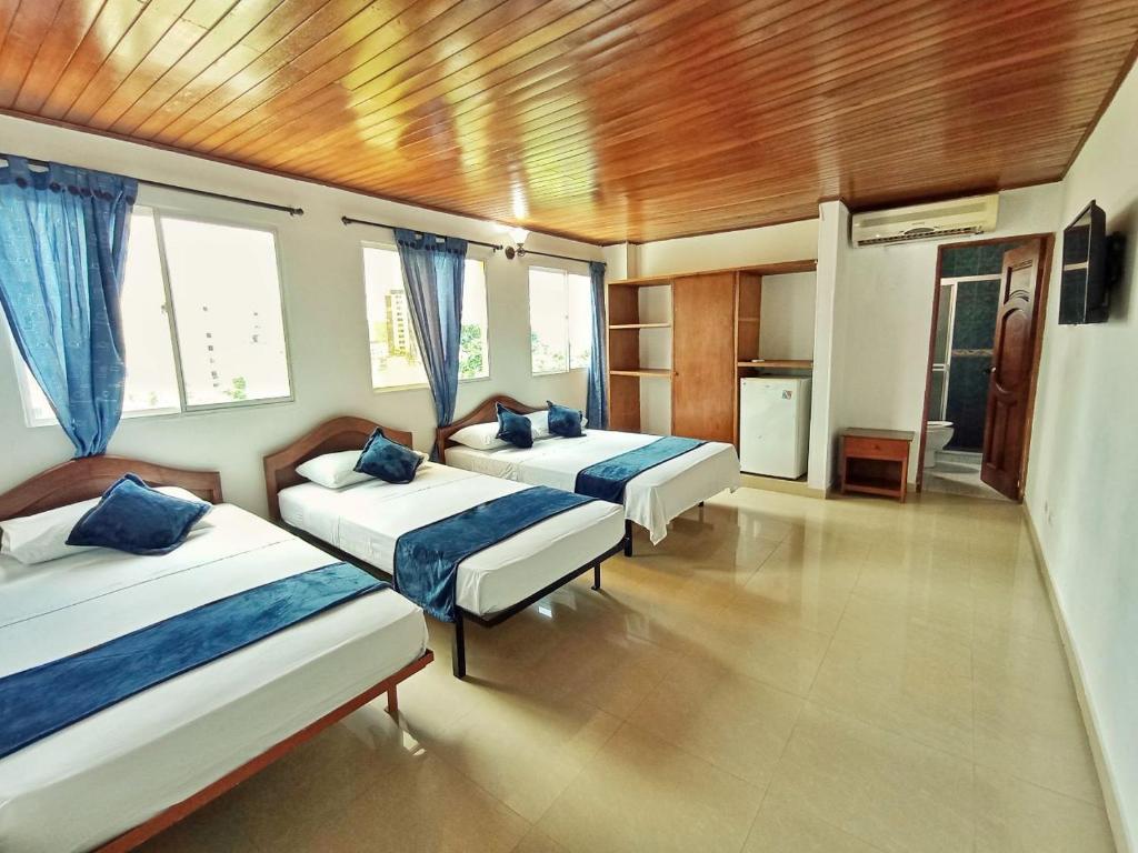 a bedroom with two beds and two windows at Hotel Rodadero Relax in Gaira
