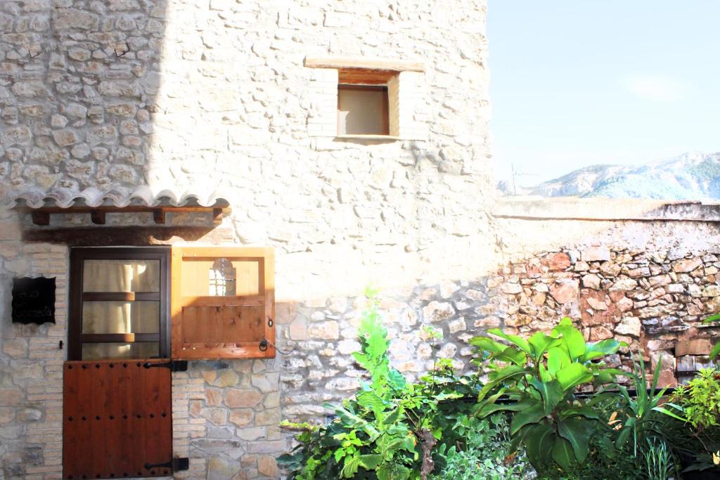 un edificio de piedra con una puerta de madera y una ventana en La Remulla, en Paüls