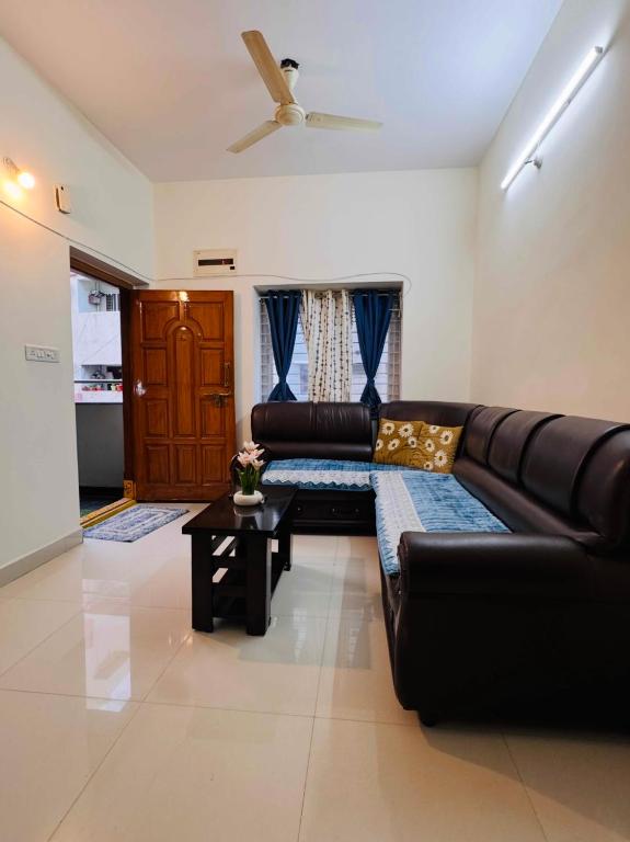 a living room with a black leather couch and a table at Indigo Homes Kondapur in Hyderabad