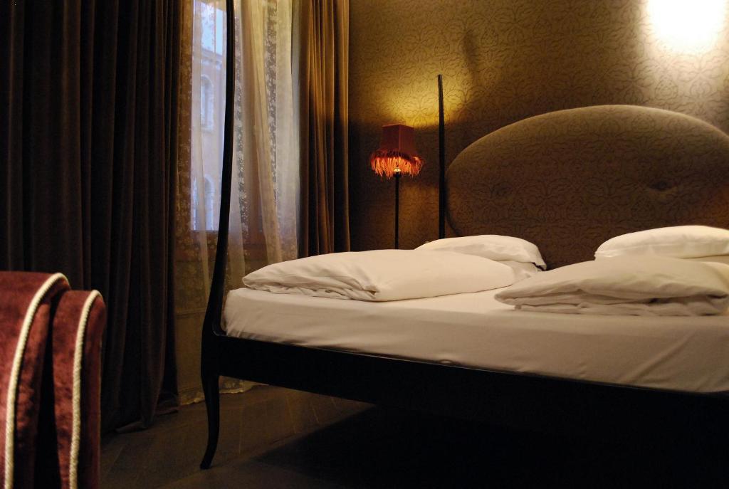 a bedroom with a bed with a headboard and a window at Hotel Palazzo Barbarigo Sul Canal Grande in Venice