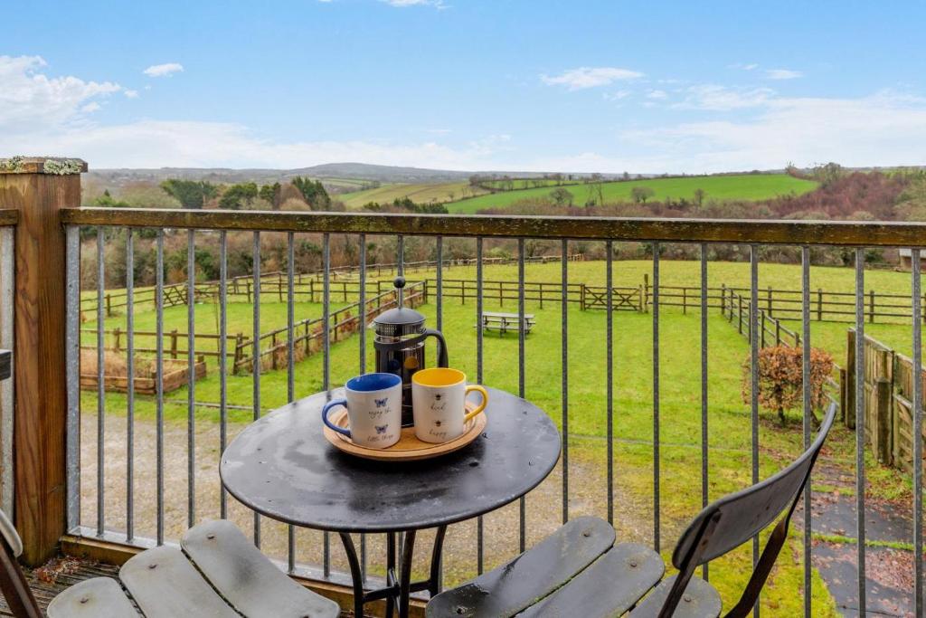 a table with two coffee mugs on it on a balcony at 4 Bed in Upton Cross oc-j34643 in Upton